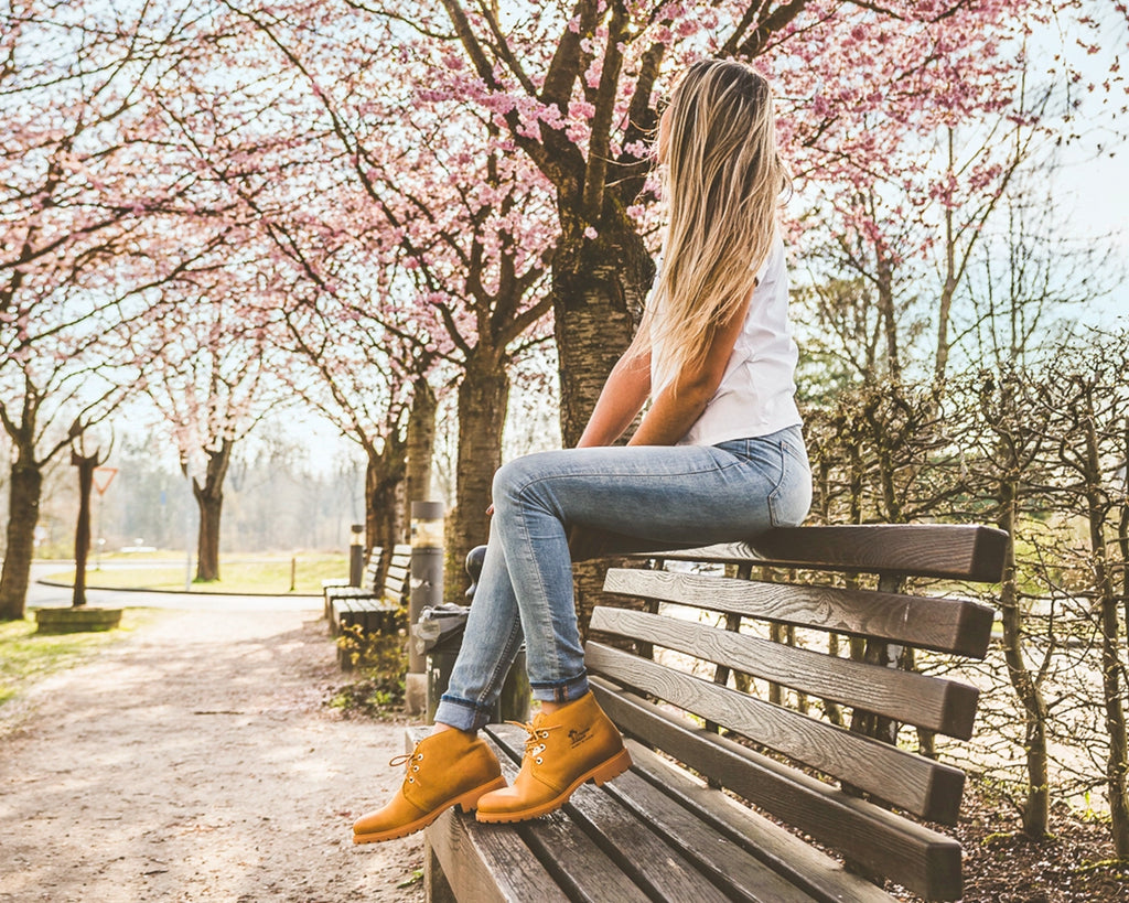 Chica sentada con Bota panama y cerezos en flor de fondo